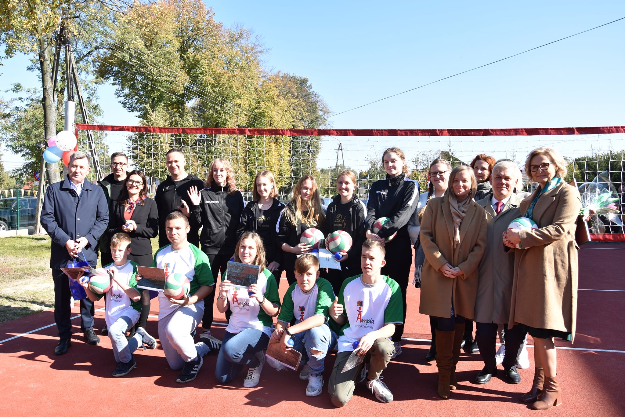 Grupowe zdjęcie. Kucają wychowankowie Specjalnego Ośrodka Szkolno-Wychowawczego w Jońcu, za nimi drużyna siatkarska, po prawej i lewej stronie zaproszeni goście.