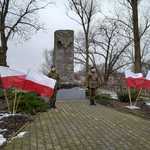Dwuosobowa warta stoi przy pomniku zamordowanych płońszczan na Piaskach po obydwu stronach stoją flagi Polski