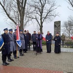 Proboszczowie płońskich parafii przemawiają pod pomnikiem na płońskich Piaskach z boku stoją poczty sztandarowe